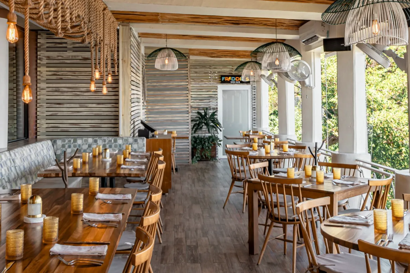 The dining room of Fred's, wooden chairs and a terrace open to the garden