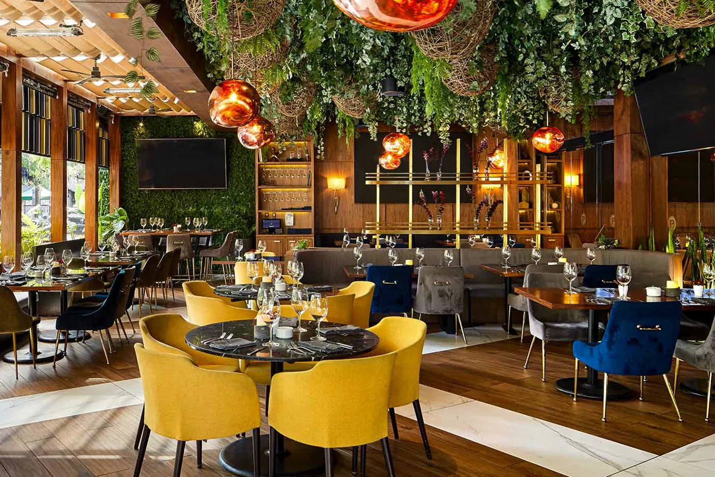 The dining room of Porfirio's, yellow chairs and plants hanging from the ceiling