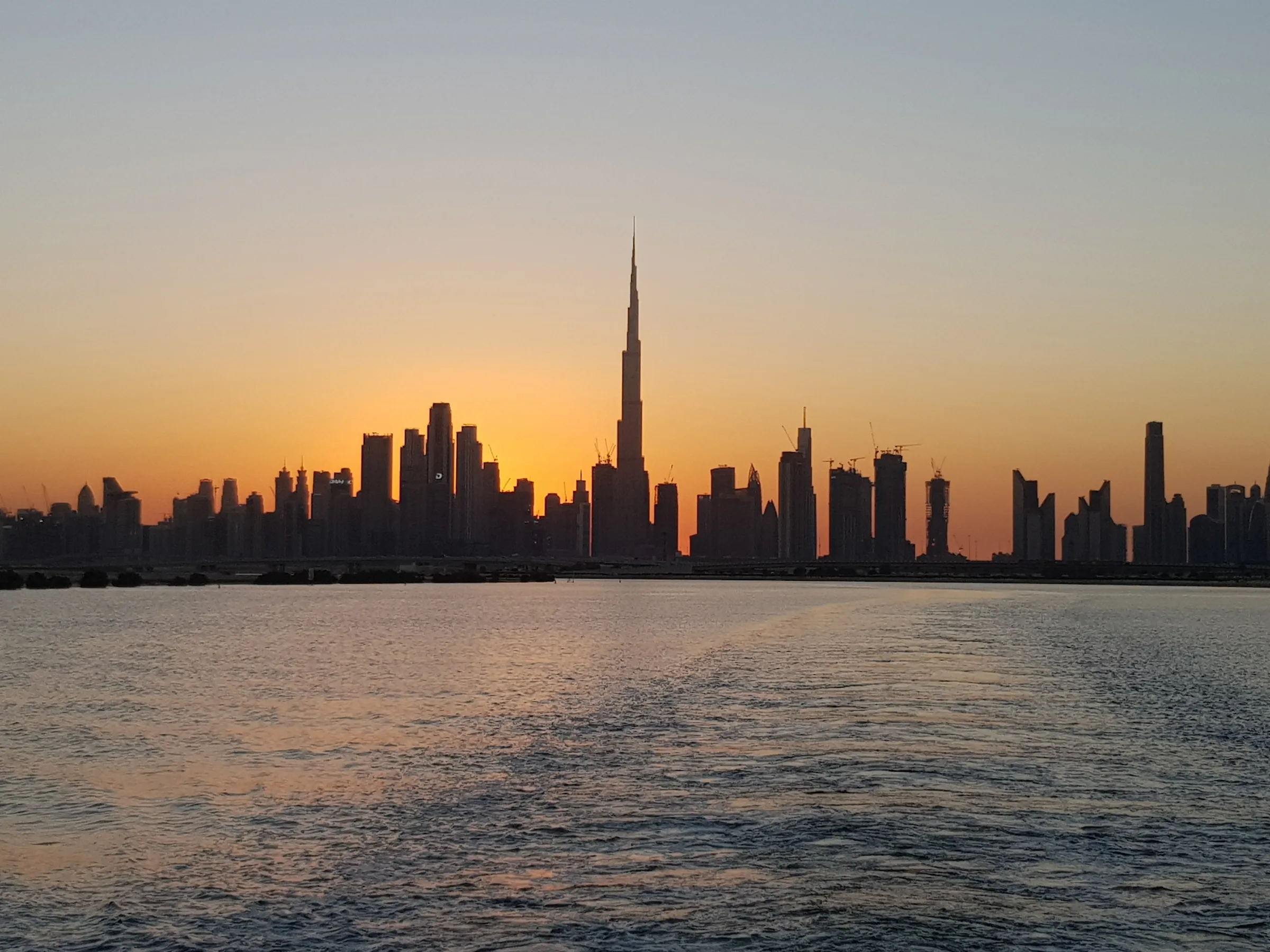The Dubai skyline and the Burj Khalifa at sunset, seen from the water